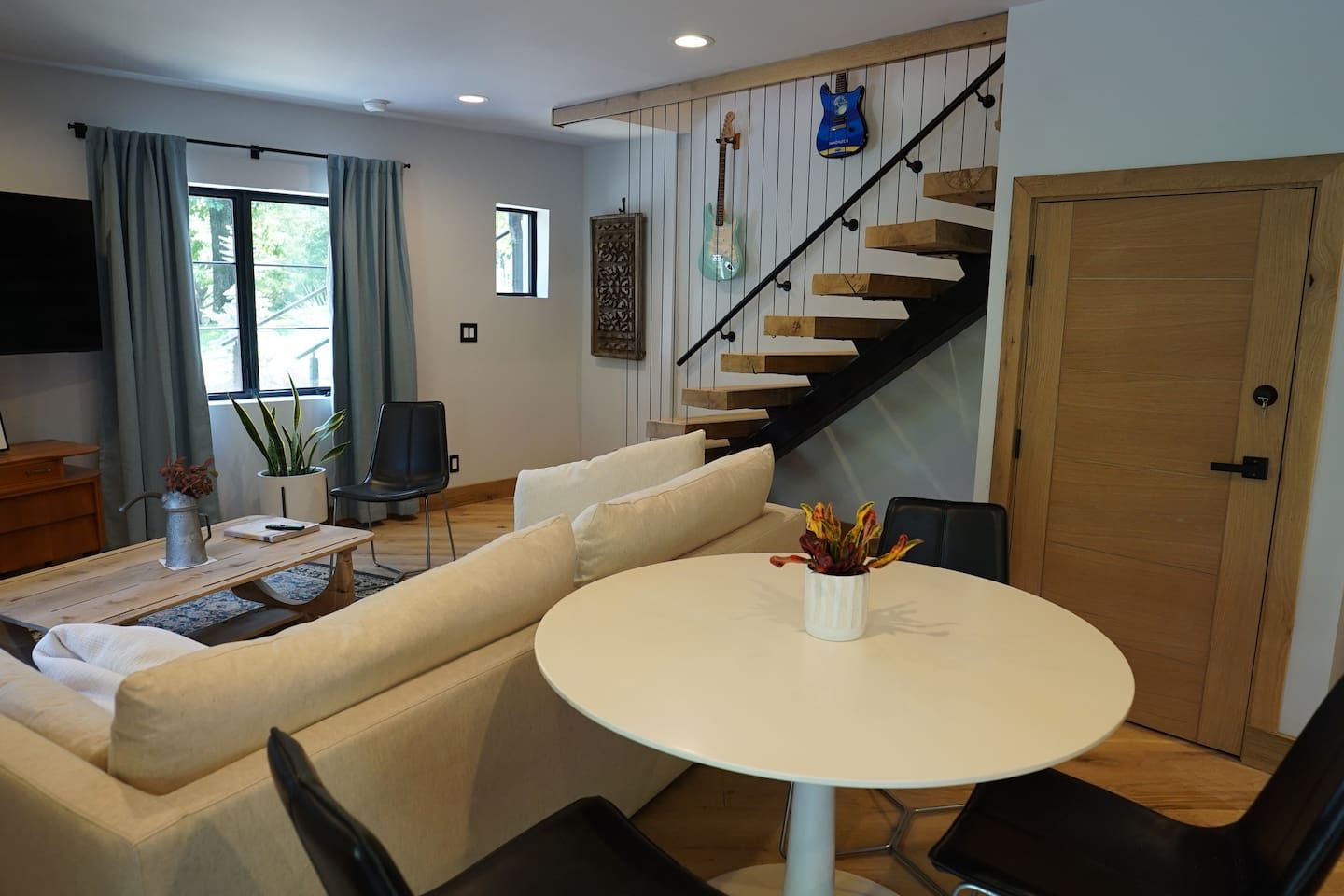 A modern living room with a sofa, a dining table, and a staircase.