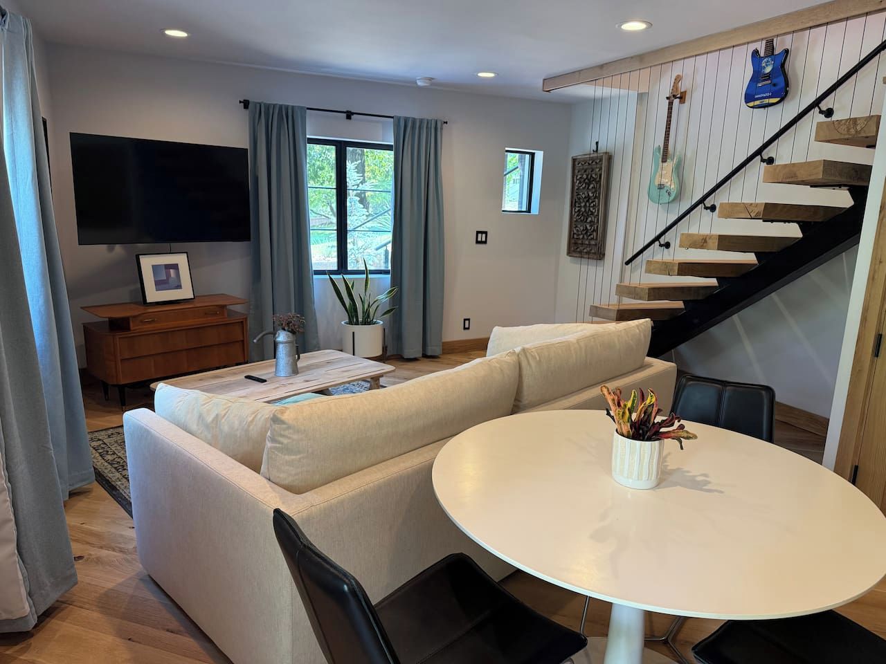 A modern living room with a sofa, a round table, and a staircase with wooden steps.
