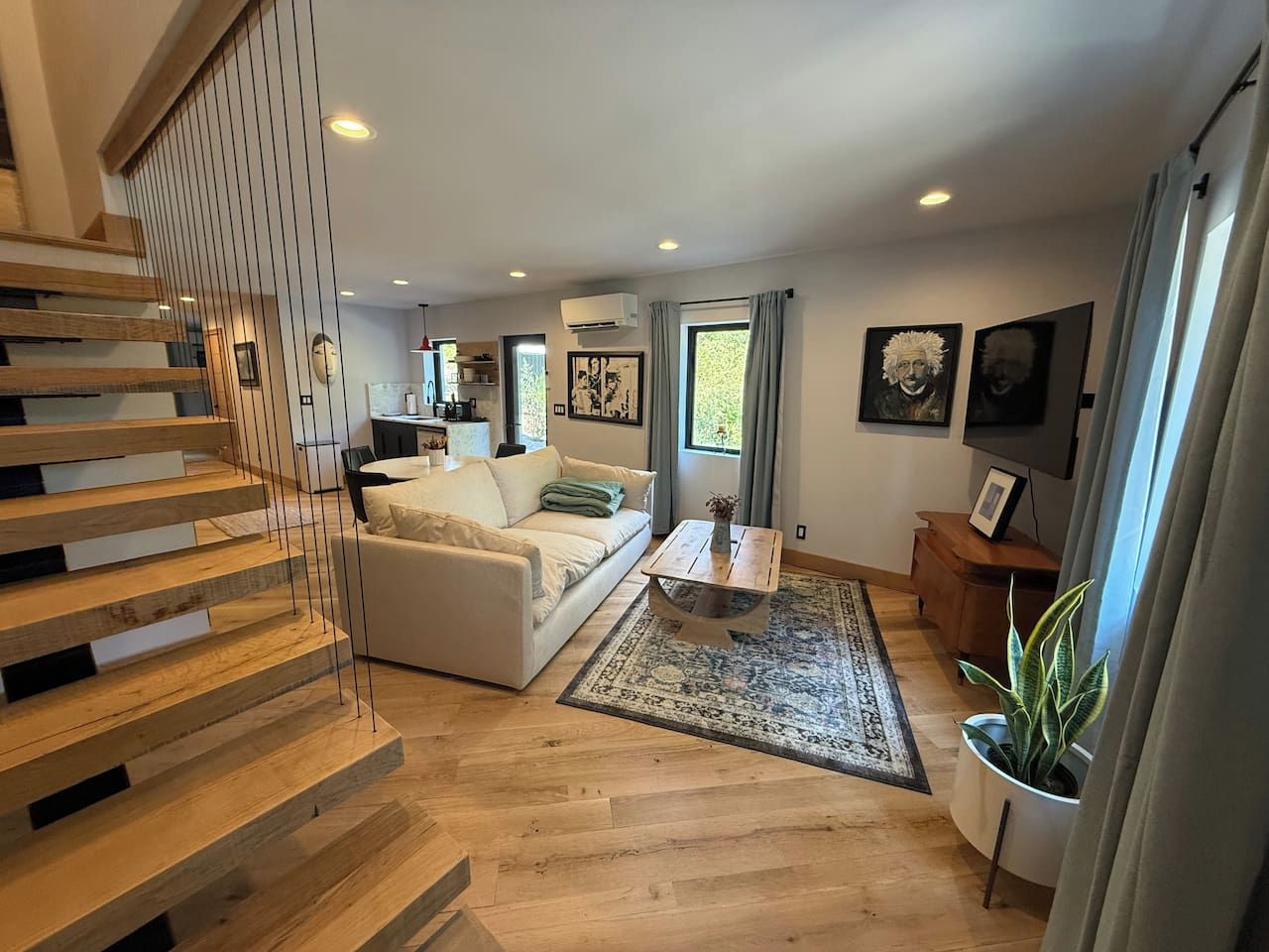 Una sala de estar moderna con una escalera, un sofá, una mesa de centro y una planta en maceta.