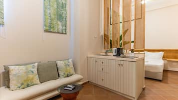 A living area with a sofa, a coffee table, a cabinet, and a bed.