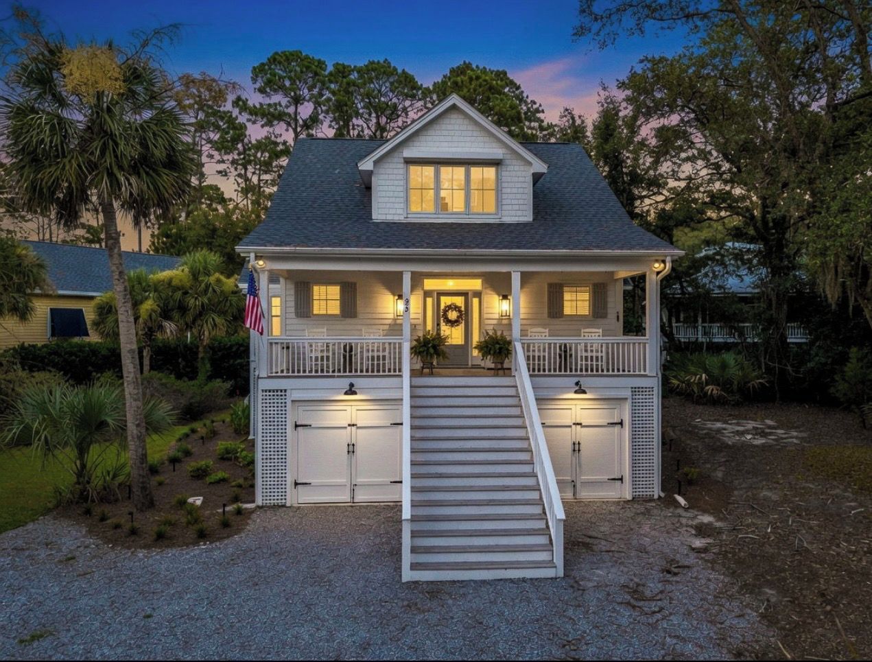 A two-story house with a front porch, a staircase leading to the entrance, and a garage with two doors.