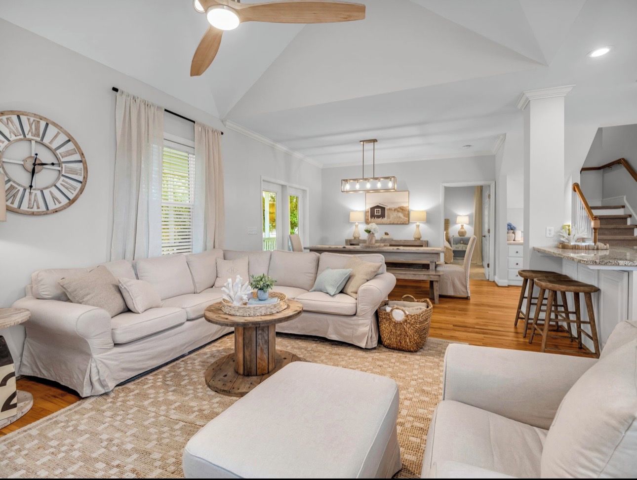A spacious living room with a sofa set, a coffee table, and a large wall clock.