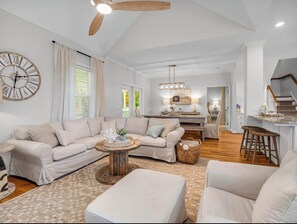 A spacious living room with a sofa set, a coffee table, and a large wall clock.