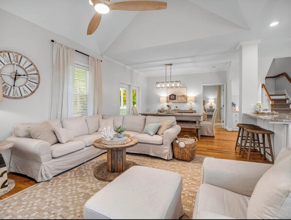 A spacious living room with a sofa set, a coffee table, and a large wall clock.