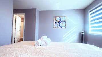 A bedroom with a large bed, a painting on the wall, and a radiator.