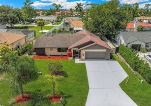 A residential area with a house featuring a garage, a driveway, and a well-maintained lawn. - The King’s Oasis - Private Pool & Coastal Vibe (Fort Myers)