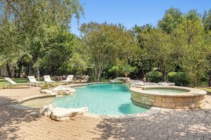 A swimming pool with a stone edge, surrounded by trees and a brick patio. - Austin Chateau Estate: Pool, Hot Tub, Saunas, Cold Plunge, Gym & Theater (Austin)