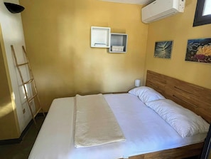 A bed with white linens, a wooden headboard, and a bedside table with a lamp. - Villa with Outdoor Kitchen and Coastal Garden (Favignana)