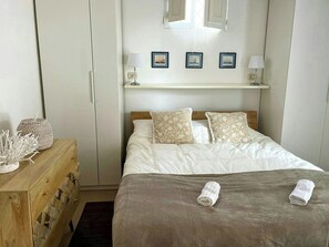 A neatly arranged bedroom with a bed, pillows, a bedside table, and a lamp. - Villa with Outdoor Kitchen and Coastal Garden (Favignana)