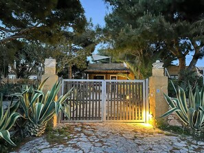A gated entrance with a stone pathway leading to a building with a tiled roof. - Villa with Outdoor Kitchen and Coastal Garden (Favignana)