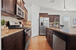 Una cocina con armarios de madera oscura, electrodomésticos de acero inoxidable y encimera de granito.