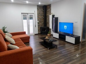 Un salon moderne comprenant un canapé, une table basse, un téléviseur à écran plat, une cheminée et une porte donnant sur un balcon.