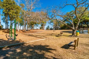 Un parc avec un banc en bois, une balançoire et une table de pique-nique.