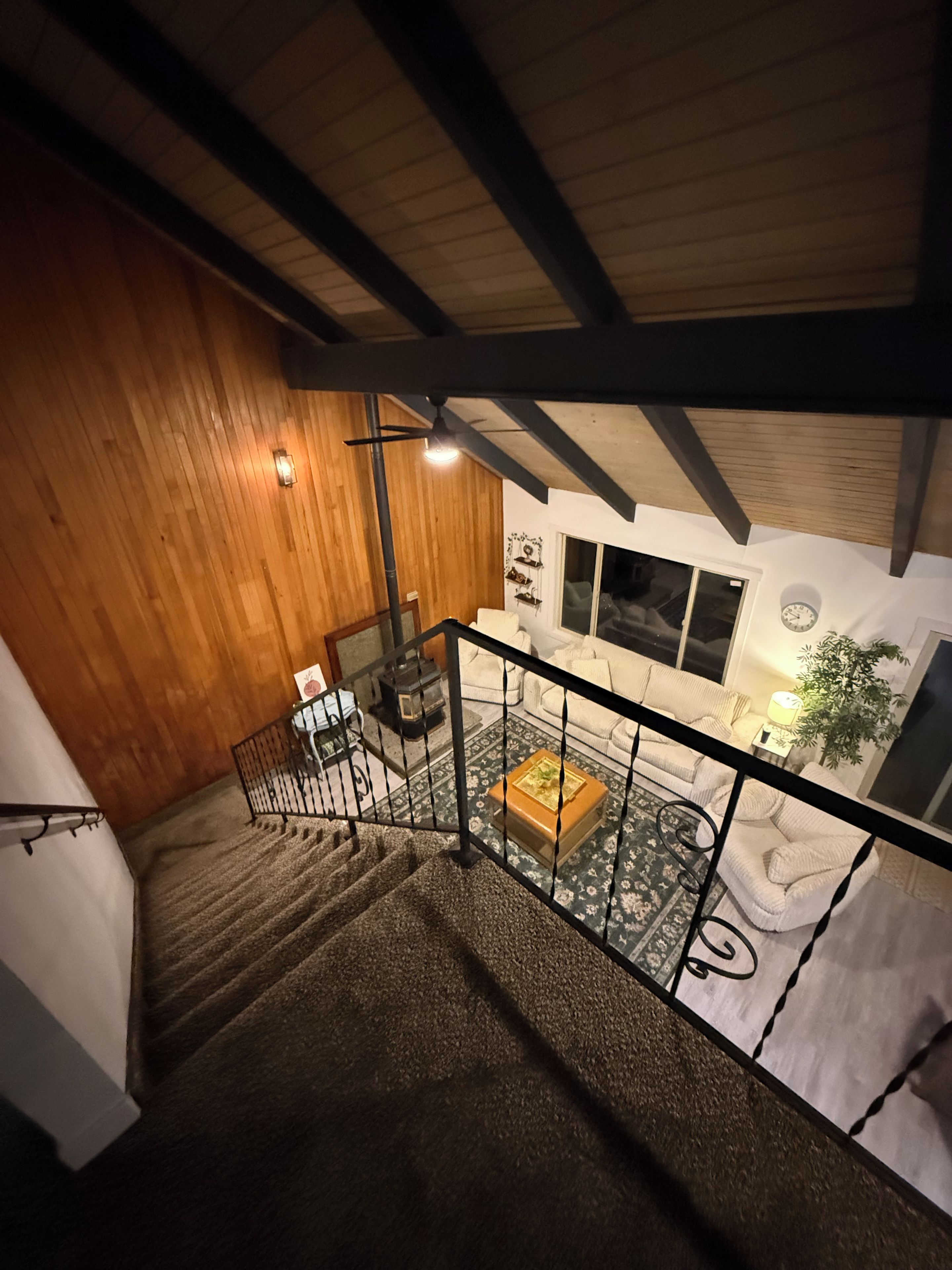 A staircase leading to a living area with a sofa, a coffee table, and a plant.