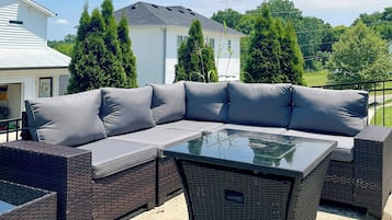A sectional sofa with cushions and a glass-top coffee table on an outdoor patio.