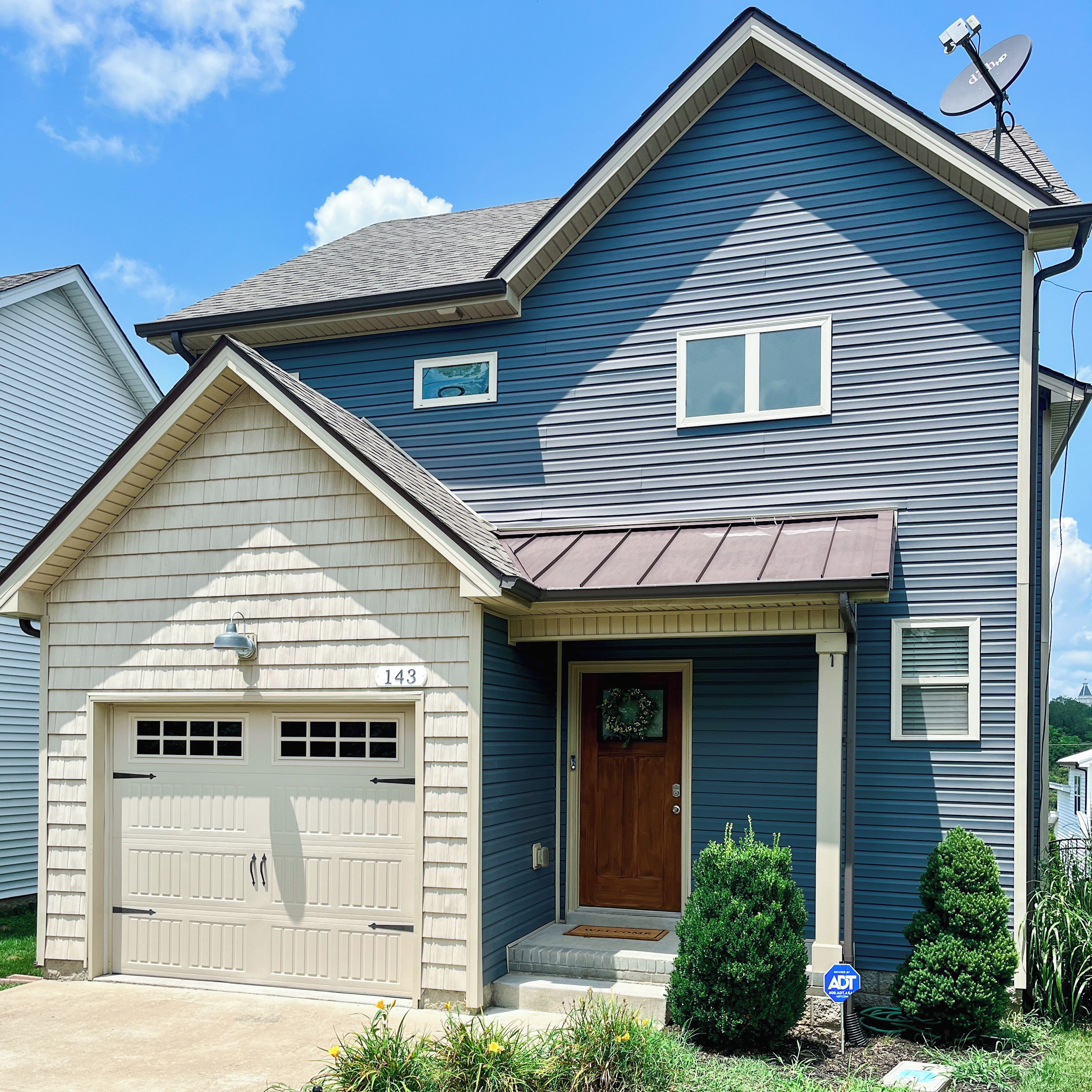 A two-story house with a garage, a front door, and a satellite dish.