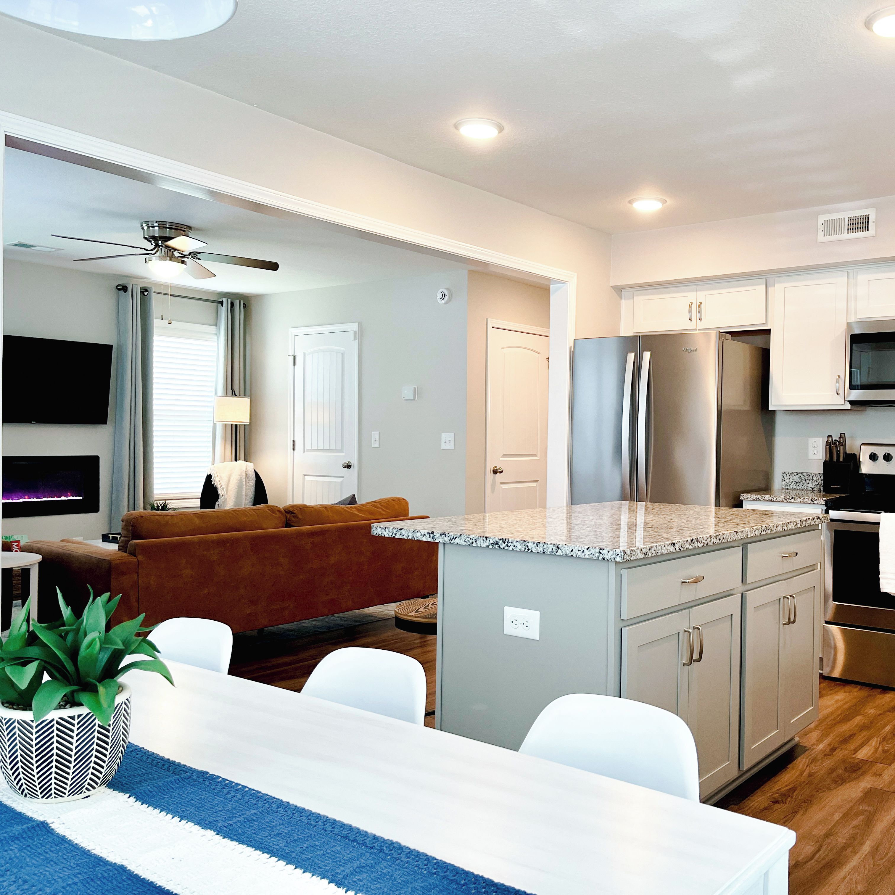A modern kitchen with a built-in island, stainless steel appliances, and a dining area with a white table and chairs.