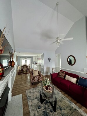 A spacious living area with a red sofa, a coffee table, and a ceiling fan. - >The Pacific Home< (Winterville)