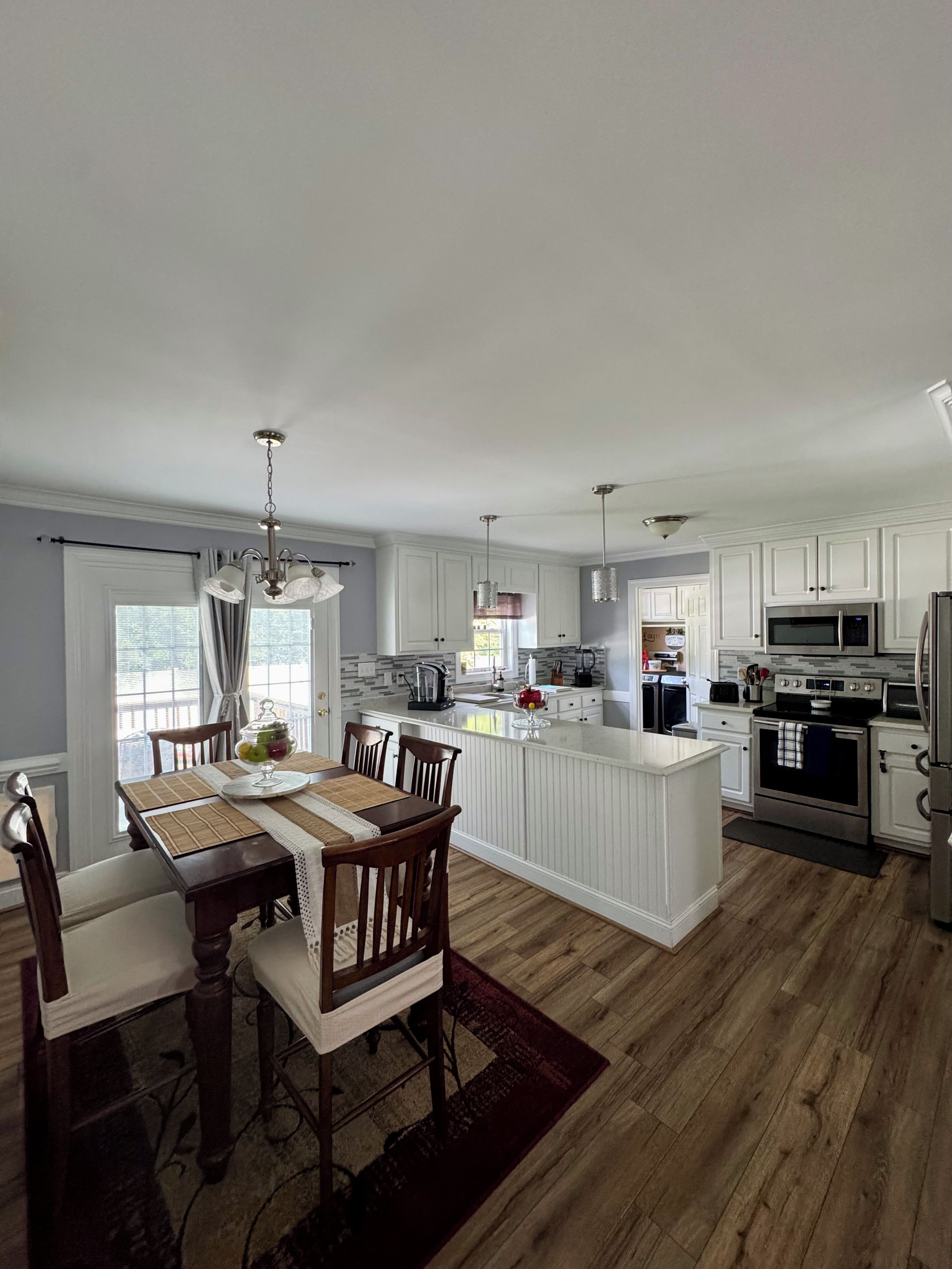 A modern kitchen with white cabinetry, a central island, and stainless steel appliances.