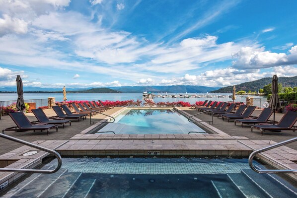 A pool area with lounge chairs and a view of the lake and mountains. - Lakefront Luxury Downtown w/ Pool, Hot Tub & Dock (Sandpoint)