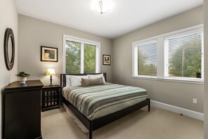 A bedroom with a bed, bedside tables, a lamp, and windows with blinds. - Lakefront Luxury Downtown w/ Pool, Hot Tub & Dock (Sandpoint)