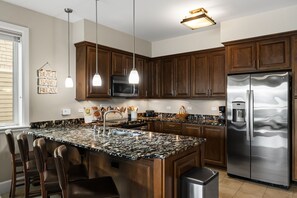 A modern kitchen with a large island, stainless steel appliances, and wooden cabinets. - Lakefront Luxury Downtown w/ Pool, Hot Tub & Dock (Sandpoint)