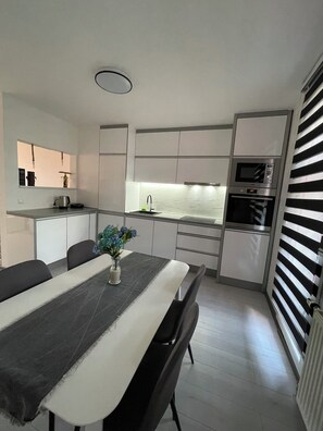 Una cocina moderna con comedor, que incluye una mesa con sillas, un florero con flores y electrodomésticos integrados.