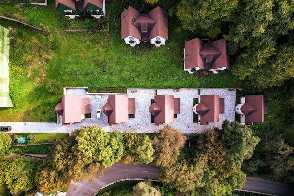 An aerial view of a property with multiple buildings, a paved driveway, and surrounding greenery.