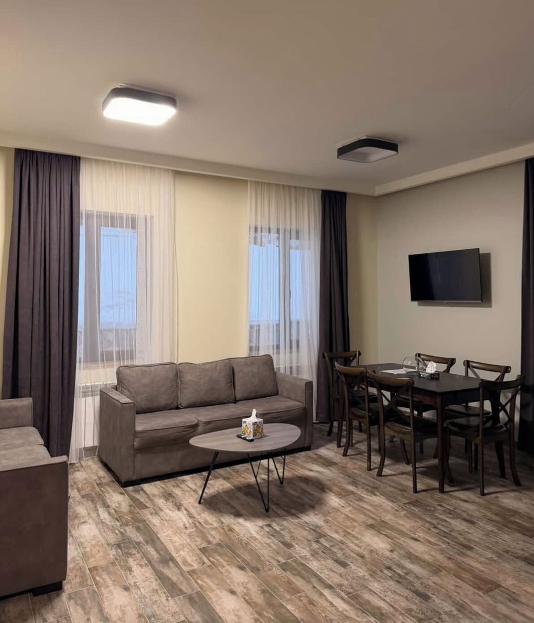 Ein modernes Wohnzimmer mit einer Couch, einem Couchtisch, einem Esstisch und Stühlen.