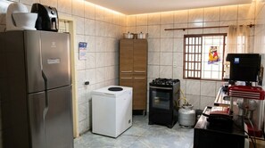 A compact kitchen with a refrigerator, a washing machine, a gas stove, and a microwave. - Vrbo Property (Foz do Iguaçu)