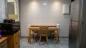 A compact kitchen with a wooden table and chairs, a microwave, a refrigerator, and a tiled backsplash. - Vrbo Property (Foz do Iguaçu)
