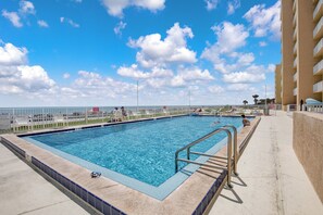 Une piscine avec un ciel bleu clair et des nuages en arrière-plan.