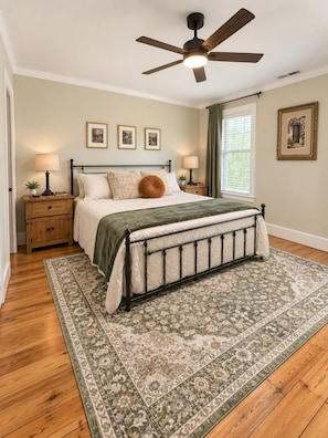 A bedroom with a bed, nightstands, a ceiling fan, framed pictures, and a window with curtains. - Historic Farmhouse / Venue in Tipp City (Tipp City)