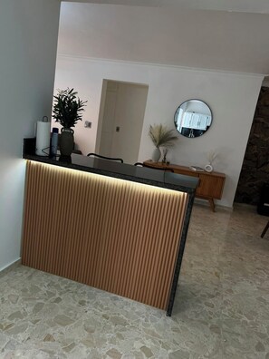 Un espace d’accueil avec un panneau en bois, un comptoir noir et un miroir au mur.