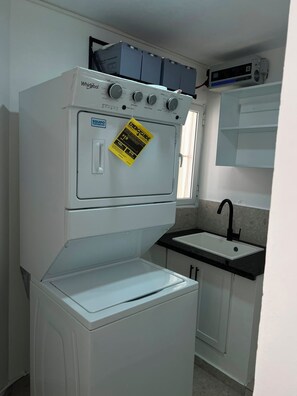 A compact kitchen with a stacked washer and dryer, a sink, and a small countertop. - Beautiful  2-Bedroom Apartment with New Appliances & AC in Costambar beach (Costambar)