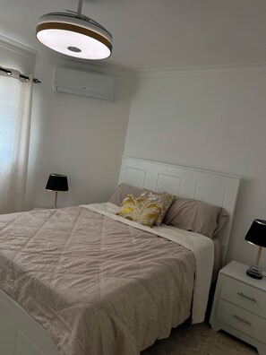 A bedroom with a bed, bedside tables, a ceiling light, and an air conditioning unit. - Beautiful  2-Bedroom Apartment with New Appliances & AC in Costambar beach (Costambar)