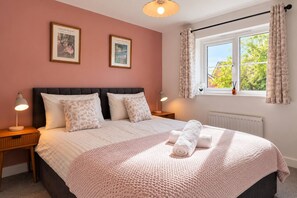 A bedroom with a bed, two bedside lamps, a window with curtains, and two framed pictures on the wall. - Spacious 4BR Home | Sleeps 8 | Parking + Garden (Quedgeley)
