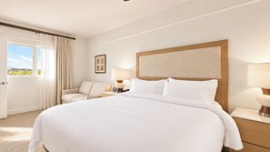 A hotel room with a large bed, a sitting area with a chair, a desk with a lamp, and a view of the outdoors. - Marriott's Gorgeous Beachfront Waiohai Club Resort + Resort Amenities Included (Koloa)