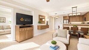 Ein modernes Wohnzimmer mit einem Flachbildfernseher, Holzschränken, einer Couch und einem Couchtisch mit Büchern und einer Pflanze.