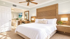 A hotel room with a large bed, wooden headboard, bedside lamps, a desk, and a bathroom visible through an open door. - Marriott's Gorgeous Beachfront Waiohai Club Resort + Resort Amenities Included (Koloa)