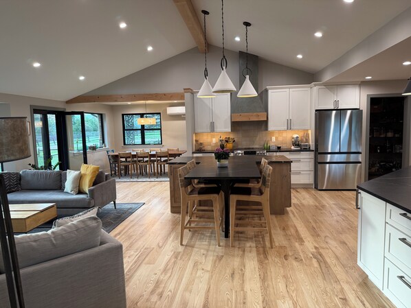 Een moderne keuken met houten vloeren, een centraal kookeiland, roestvrijstalen apparatuur en hanglampen.