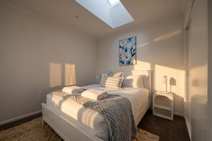 Ein Schlafzimmer mit Dachfenster, einem Bett mit Kissen, einem Nachttisch und einem Wandbild.