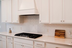 Eine Küche mit weißen Schränken, einem Gasherd und einer backsplash in Fischgrätmuster.