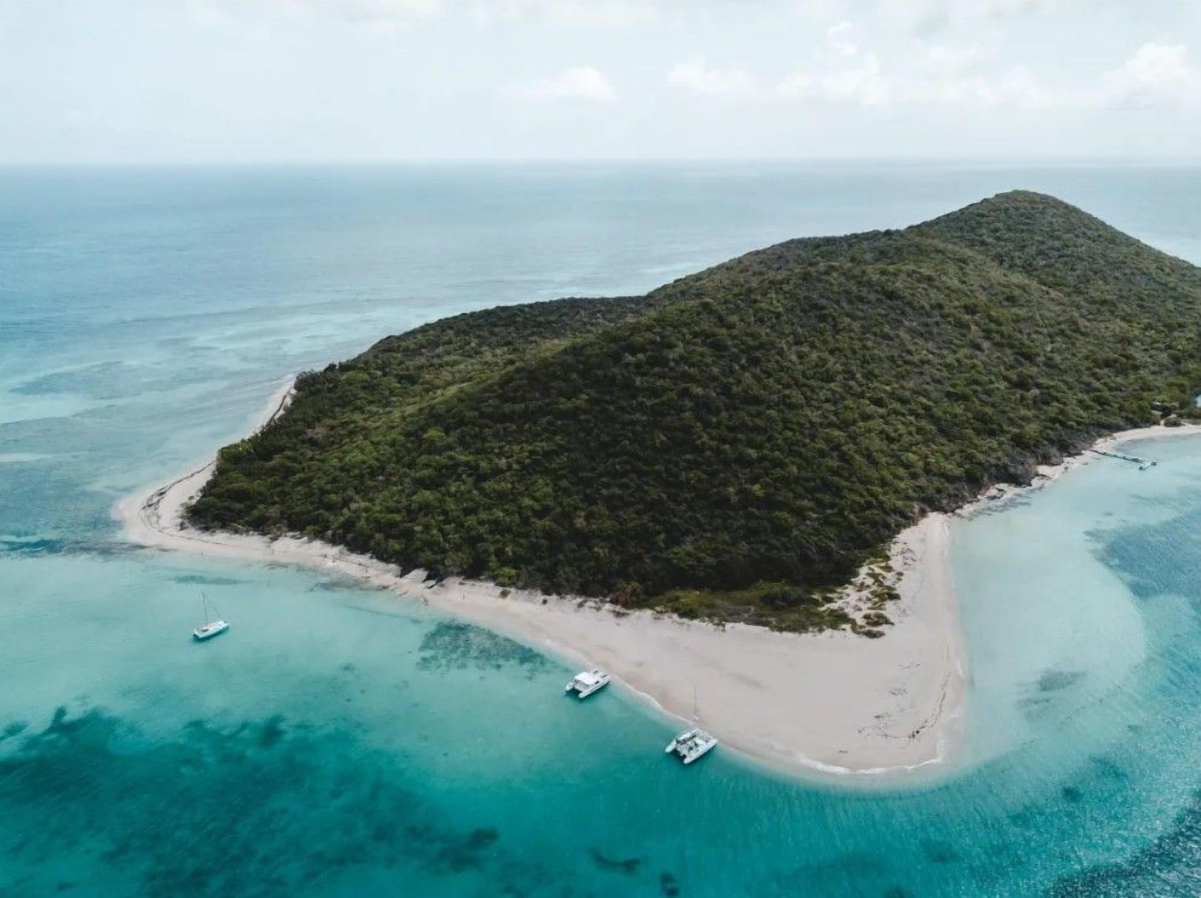 An aerial view of a tropical island with a beach and boats.