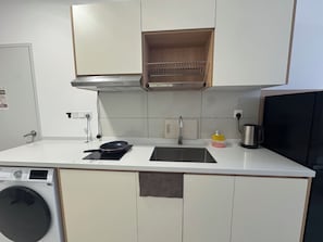 A compact kitchen with a washing machine, a stove, a sink, and a coffee maker. - Majestic Residence KLCC by Uniquehome (Kuala Lumpur)