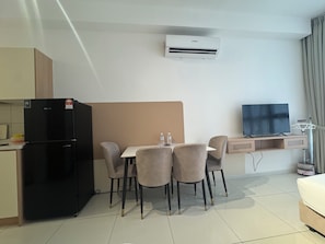 A hotel room with a kitchenette, a dining area with a table and chairs, a flat-screen TV, and an air conditioning unit. - Majestic Residence KLCC by Uniquehome (Kuala Lumpur)