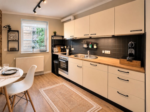 A modern kitchen with white cabinets, a black backsplash, and a wooden countertop. - Vrbo Property (Adenbüttel)