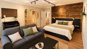 A modern bedroom with a bed, a sofa, a small table, and a wooden headboard. - Vrbo Property (Adenbüttel)