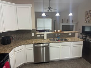 A kitchen with white cabinets, a granite countertop, a dishwasher, and a ceiling fan. - Awesome 3-bedroom house with AC in quaint Denham Springs (Denham Springs)