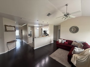 A spacious living area with a dark hardwood floor, a red sofa, and a ceiling fan. - Awesome 3-bedroom house with AC in quaint Denham Springs (Denham Springs)